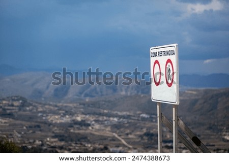 Restricted area or zone sign on top of the Puig de la Llorenca on a clear sunny day overlooking Cumbre Del Sol. English translation- RESTRICTED AREA