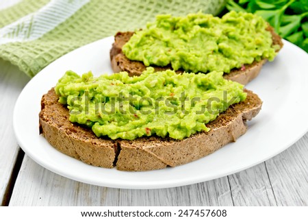 Two slices of rye bread on a plate with guakomole, napkin, parsley on the background light wooden boards Royalty-Free Stock Photo #247457608