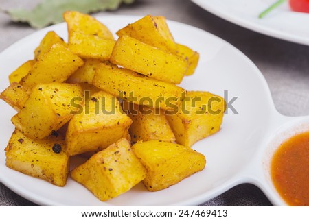Fried potato cubes  with sauce on a wooden table