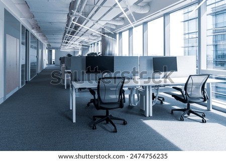 This contemporary office space features a clean, open layout designed for productivity and collaboration. The large windows allow an abundance of natural light to illuminate the room.