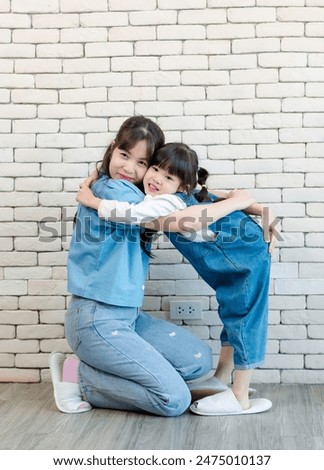 Happy asian beautiful young mother and cute daughter little girl smiling  posing kissing on white brick wall background studio portrait Mother's Day love family parenthood childhood concept.