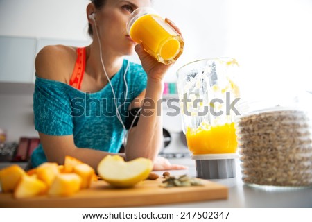 Close-up on fitness young woman drinking pumpkin smoothie in kitchen Royalty-Free Stock Photo #247502347