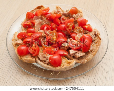 Dried bread called freselle with tuna and tomatoes on wooden table