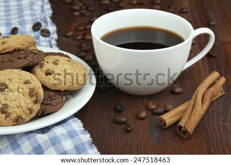 Plate with chocolate cookies and cup of hot coffee on old wooden table. 