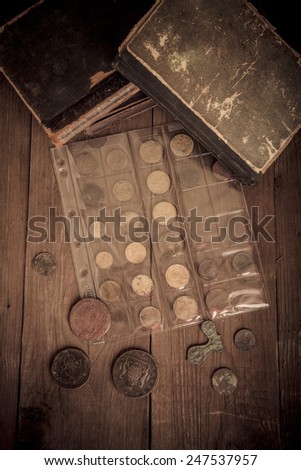 Vintage books and coins on old wooden table. Toned.