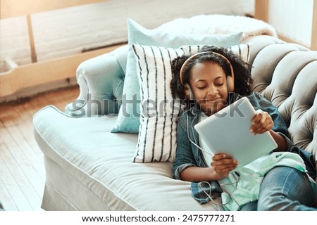 Happy girl, headphones and relax with tablet on sofa for online streaming, entertainment or listening to music at home. Young female person, child or teenager with smile on technology for audio