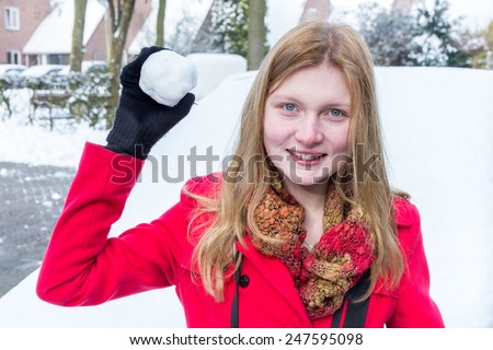 Young woman dressed in red holding snowball