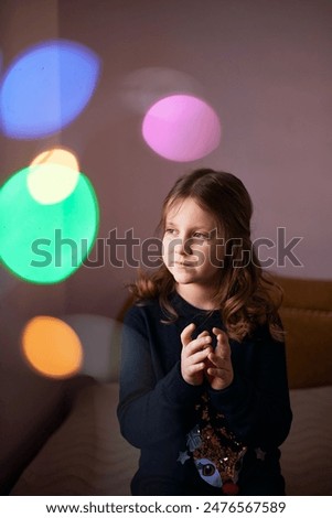 portrait of a girl in lights New Year's colored lights 7 years old laughs advertising