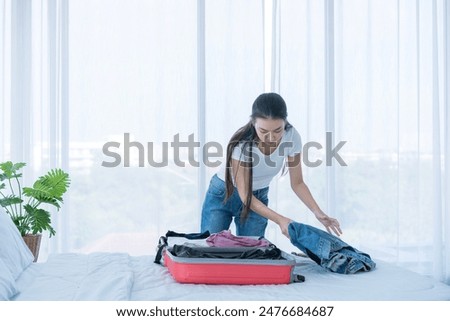 Young women travelers in summer. A woman happily packing a bag for traveling. Young woman packing bag for holiday.