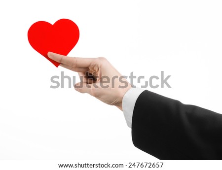 Valentine's Day and love theme: a man in a black suit holding a red heart isolated on a white background in studio