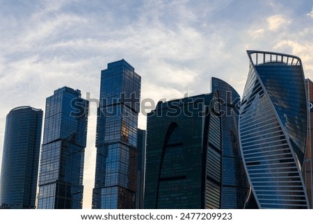 A view of the Moscow skyline, featuring several modern skyscrapers against a backdrop of blue sky and clouds.