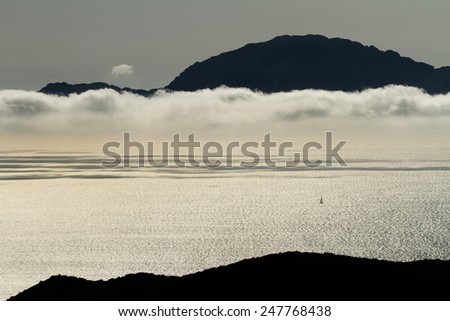 view to the ocean, clouds and a yacht with silhouette of mountains on a background