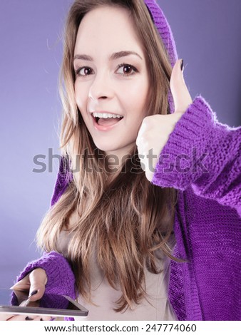 Technology and communication. Happy smiling woman teenage girl texting on mobile phone, using smartphone reading sms message making thumb up hand sign gesture on violet