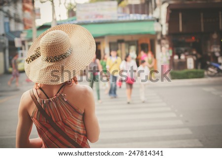 A young woman is walking on the street of an asian country on a sunny day