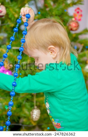 blond little boy dresses up Christmas tree toys