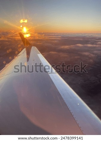 Photo of the sun rising over the top of an airplane wing 