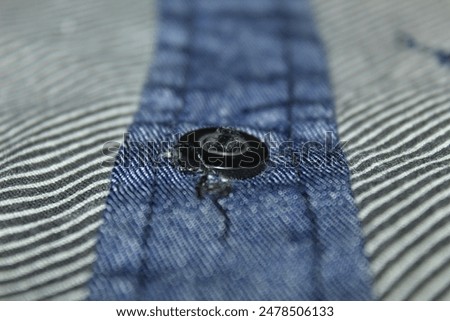Black buttons on a gray shirt with a black striped pattern photographed close up