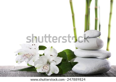 Still life of spa stones on bamboo mat surface with bamboo sticks isolated on white