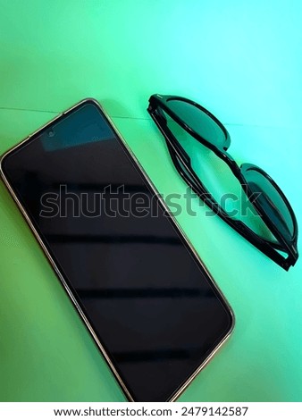 Mobile and goggles:mobile and sunglasses on the green isolated, green background 