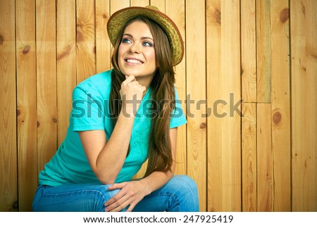 Happy young woman portrait in American country style. Yellow hat. Wooden background.