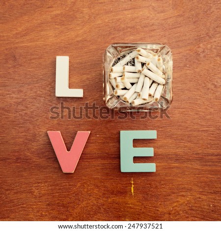 word love made up of colorful wooden letters with ashtray instead of letter O on a wooden board. February 14, Valentine's Day