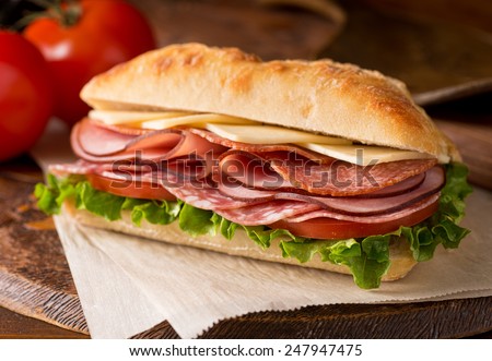 A delicious sandwich with cold cuts, lettuce, tomato, and cheese on fresh ciabatta bread. Royalty-Free Stock Photo #247947475
