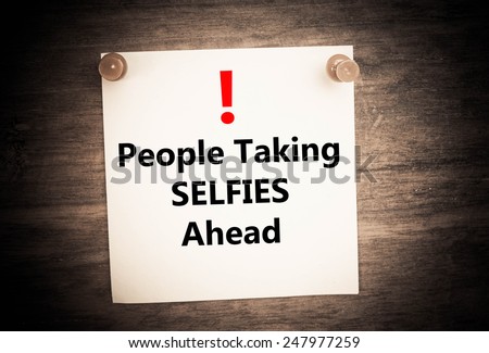 a warning about people taking selfies concept on note paper
