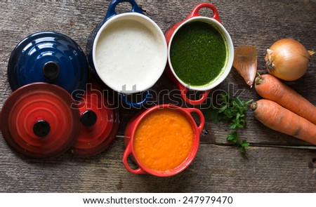 Different kinds of soups - sprinach soup, french onion cream-soup and carrot cream-soup on the table