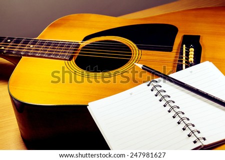 black pencil with white notebook on the guitar