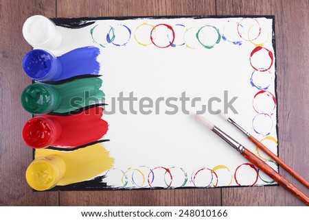 Colorful paint strokes on sheet of paper and wooden table background