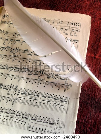 Old music partiture and white feather over red background