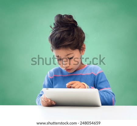 education, school, technology and children concept - little student girl with tablet pc over green chalk board background
