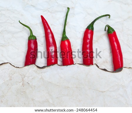 fiery red chili peppers under a sheet of paper with the scorched edge