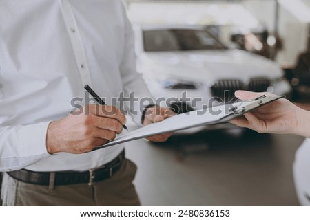Cropped close up man customer male buyer client signs contract documents with salesman choose auto want to buy new automobile in car showroom vehicle salon dealership store motor show. Sales concept