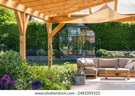 covered terrace with furniture in the garden, glasshouse in the background