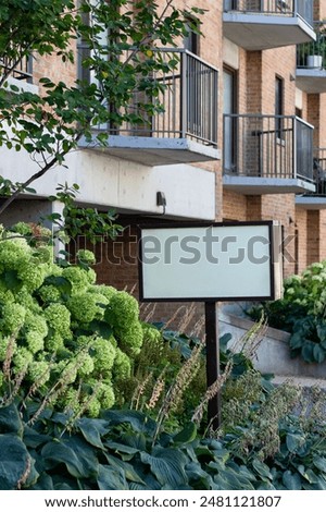 Blank advertisement sign for sale or rent near residential house. Apartment building or retirement home.