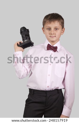teenager boy in a pink shirt in a bow tie with a camera in hand