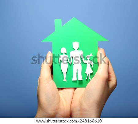 Cutout house with paper family in female hands on colorful background