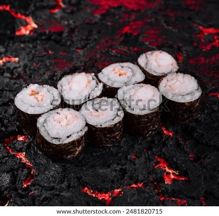 Aesthetic image of sushi rolls arranged on a rugged black lava surface with fiery red highlights
