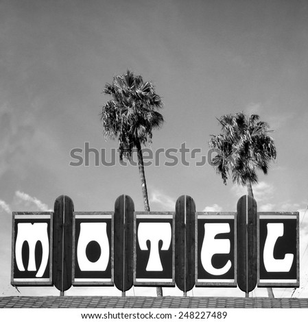  black and white aged and worn vintage photo of motel sign with palm trees                           