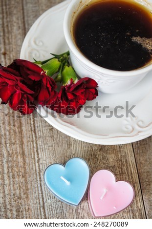 Cup of tea, red cloves flowers and heart shaped candles