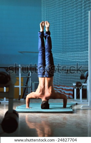 Young man performing  handstand in fitness studio. rear, back perspective.