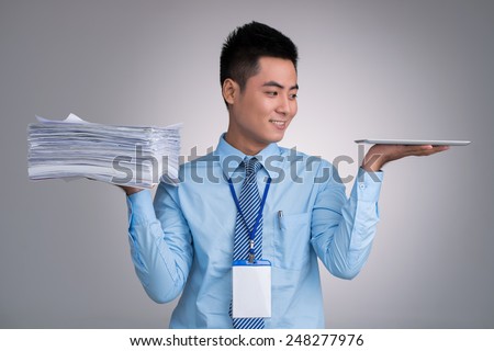 Smiling Vietnamese manager with pile of documents in one hand and digital tablet in another Royalty-Free Stock Photo #248277976
