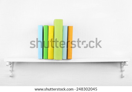 Colorful covered books on bookshelf and white wall background