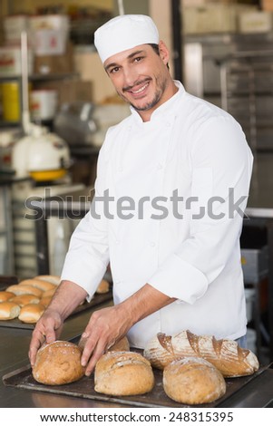 Baker checking freshly baked bread in the kitchen of the bakery