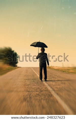 Retro picture of rear view of man with umbrella on the road
