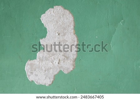 A worn-out green wall with flaking paint, perfect for backgrounds or decoration.