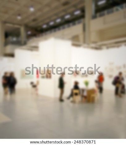 People visit an art exhibition. Intentionally blurred post production.