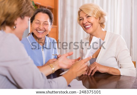 Cheerful smiling female pensioners taking legal advice from public notary