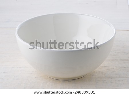Empty white bowl on wooden table Royalty-Free Stock Photo #248389501